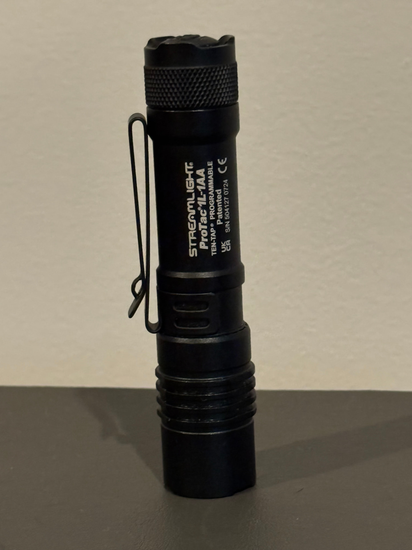 Detail shot of the ProTac 1L-1AA showing the pocket clip, knurled body, and rubber tail switch