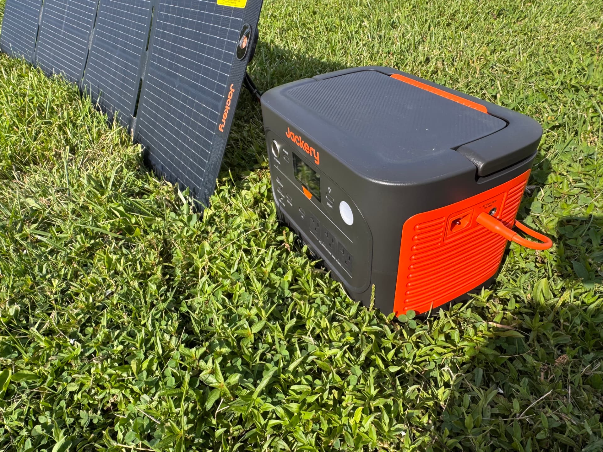 Jackery Explorer 1500 charging from portable solar panels outdoors in a grass field
