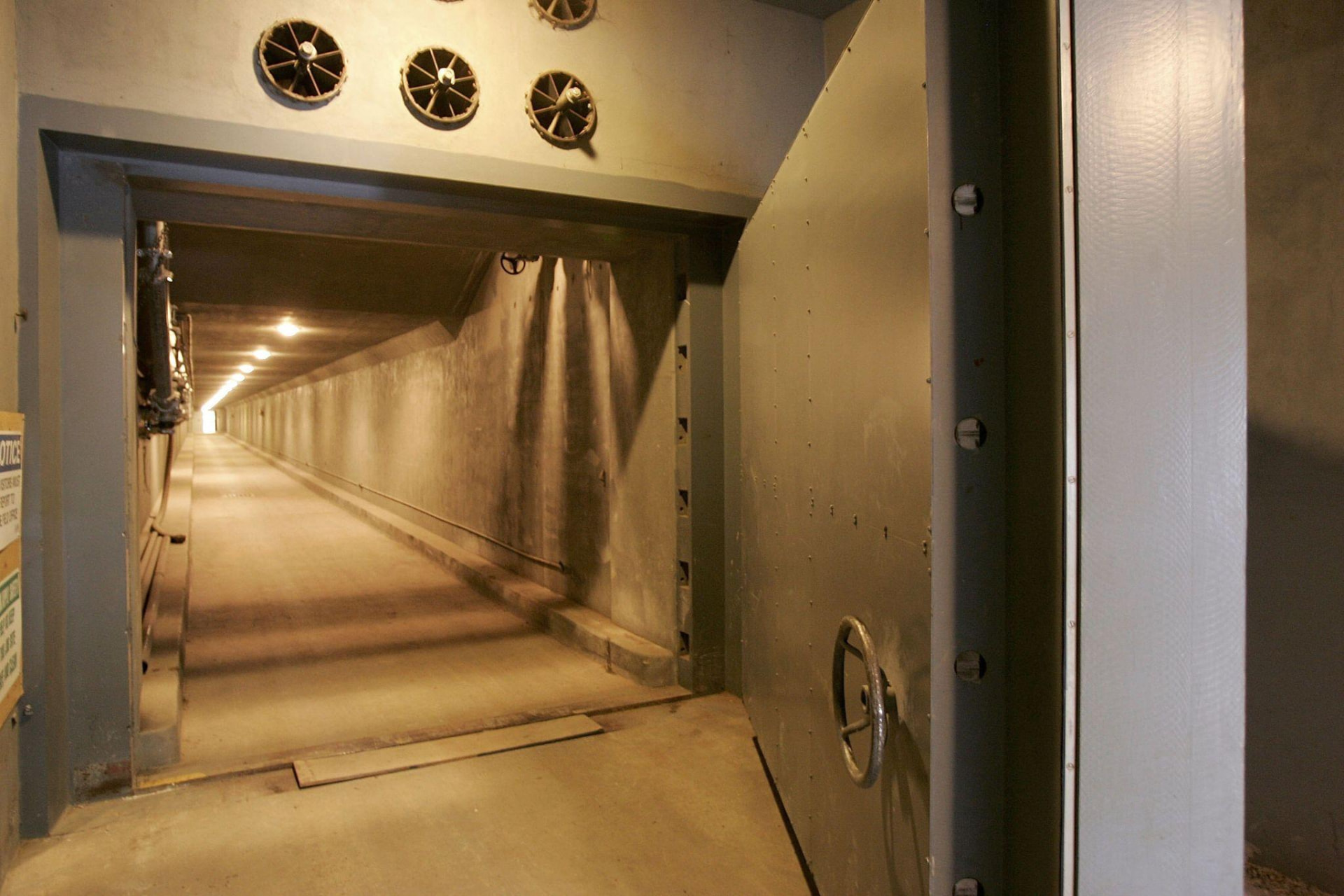 A long concrete access tunnel inside the Greenbrier bunker, with a heavy steel blast door standing open in the foreground