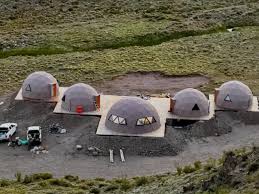 Row of geodesic dome structures under construction on excavated ground at a remote site