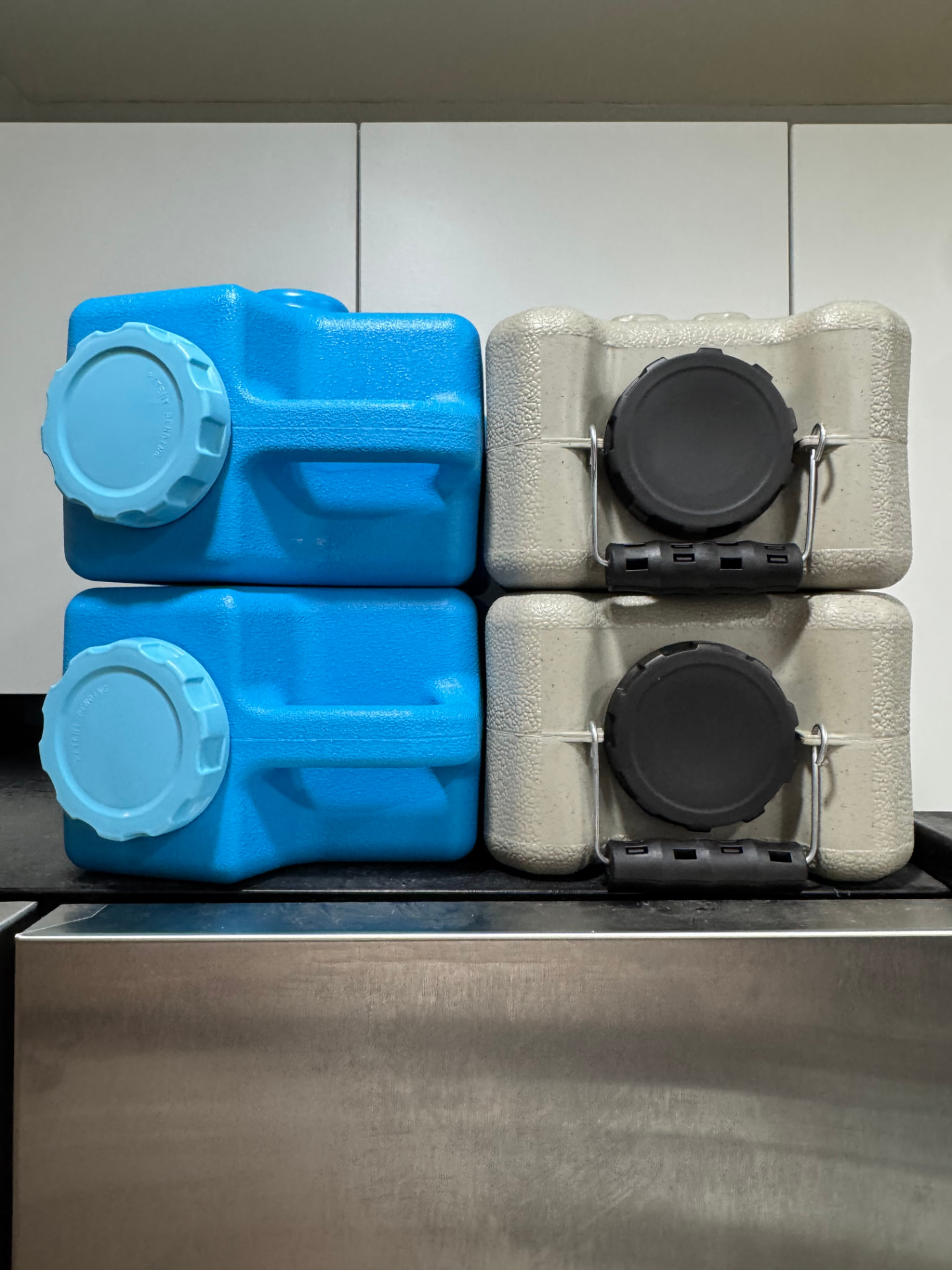 Front view of two stacked blue AquaBrick containers next to two stacked earth-tone WaterBrick containers