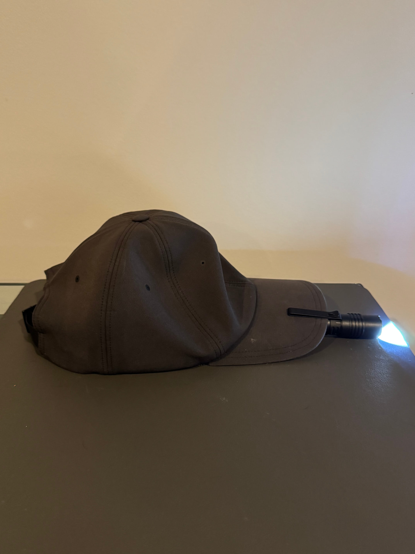 The ProTac 1L-1AA clipped to the bill of a hat and switched on