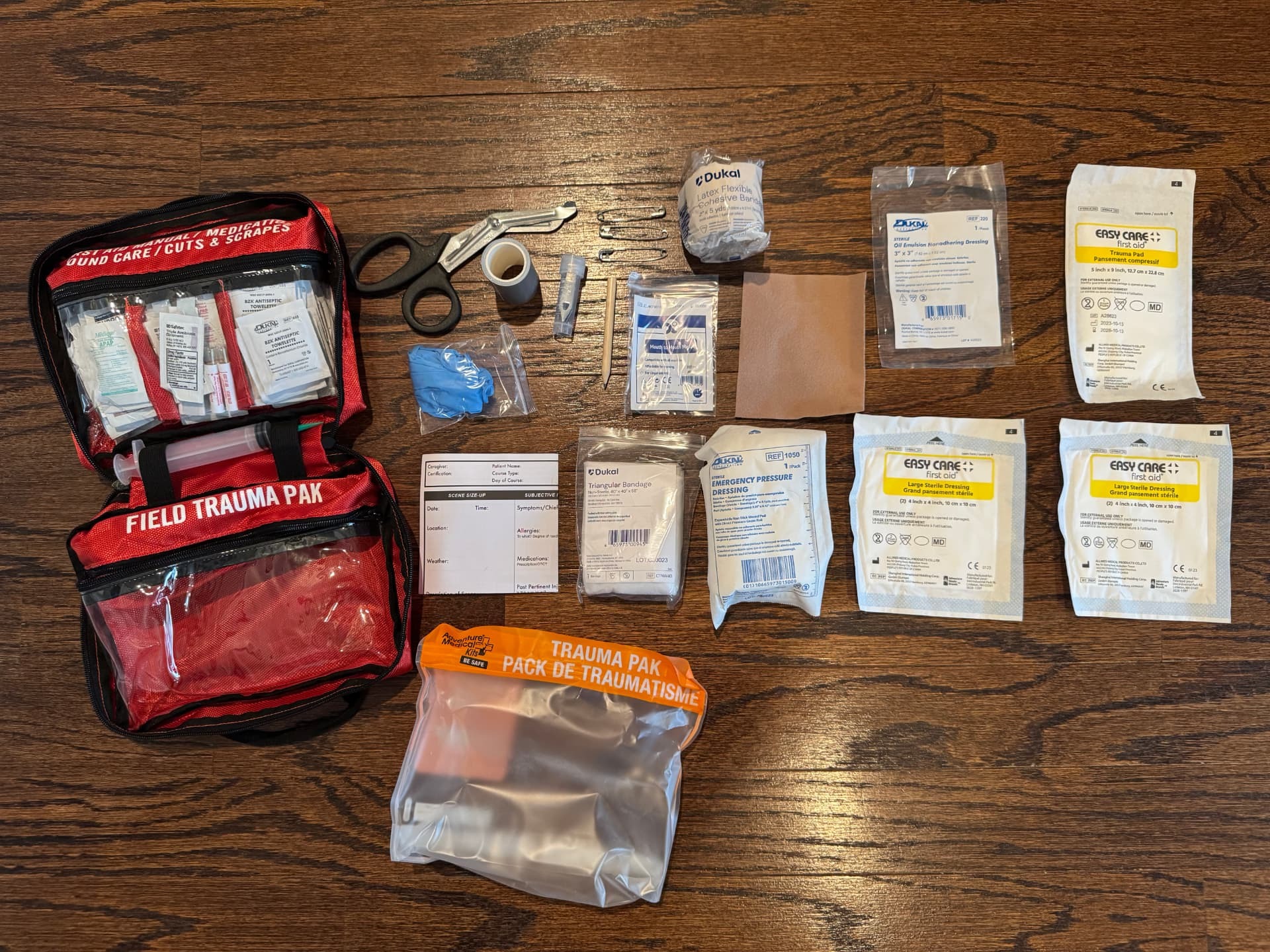 Full contents of the Sportsman 300's bottom pocket, including the Field Trauma Pak, laid out on a wood floor
